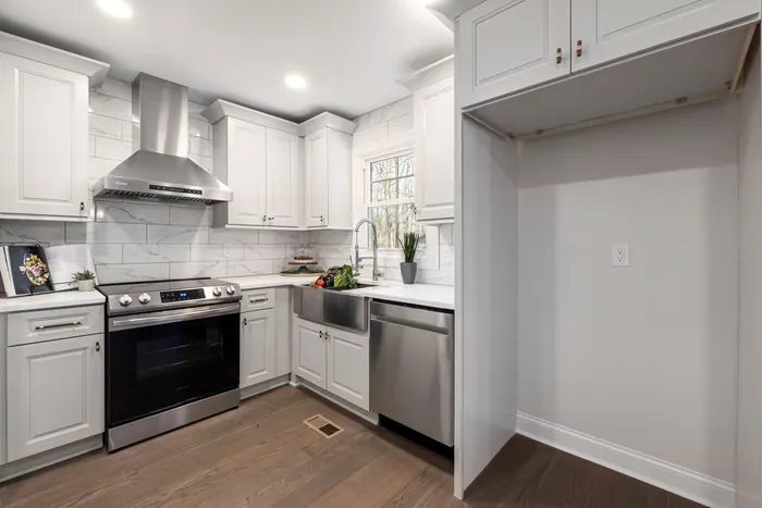 White kitchen with a stainless range and tile backsplash